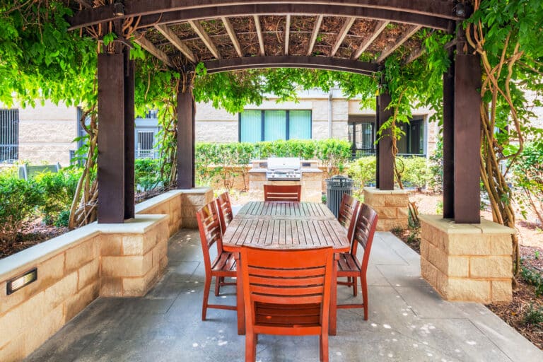 Gorgeous outdoor grills and tables in the serenity garden at Lofts at Lakeview Apartments.